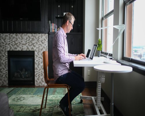 Person taking a break from laptop work, stretching slightly at desk